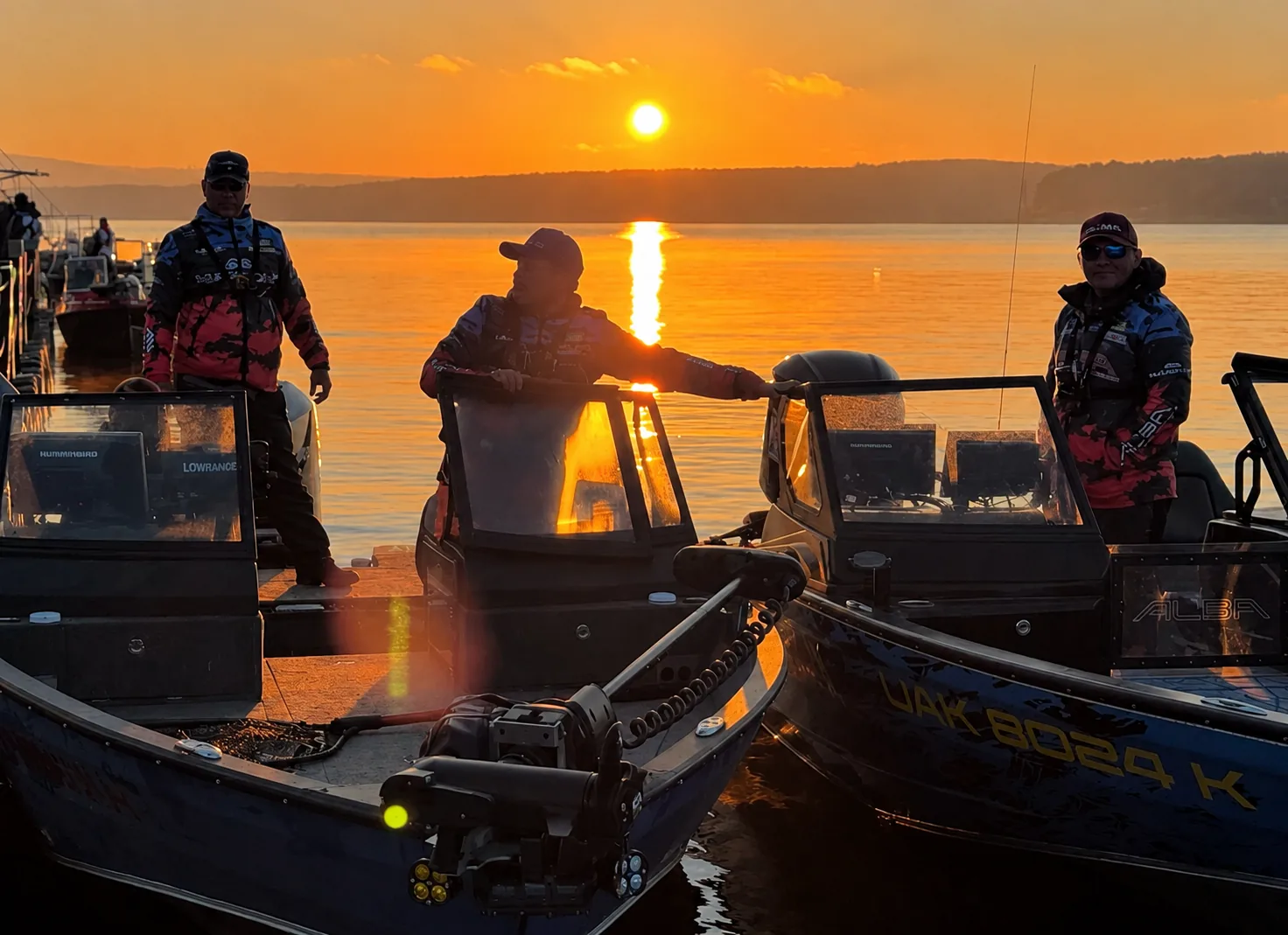 MARINAC anglers standing in their boats on the water at sunset.